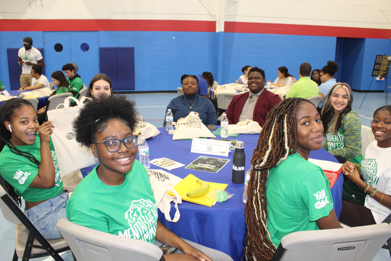 Group of Club teens at table smiling at camera
