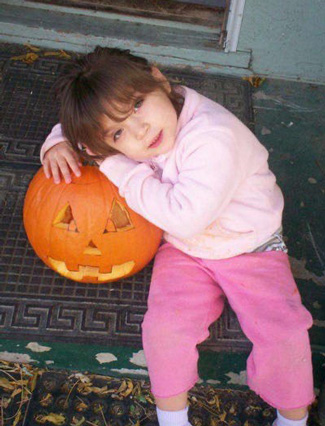 Dalilah as a little girl with a jack o'lantern
