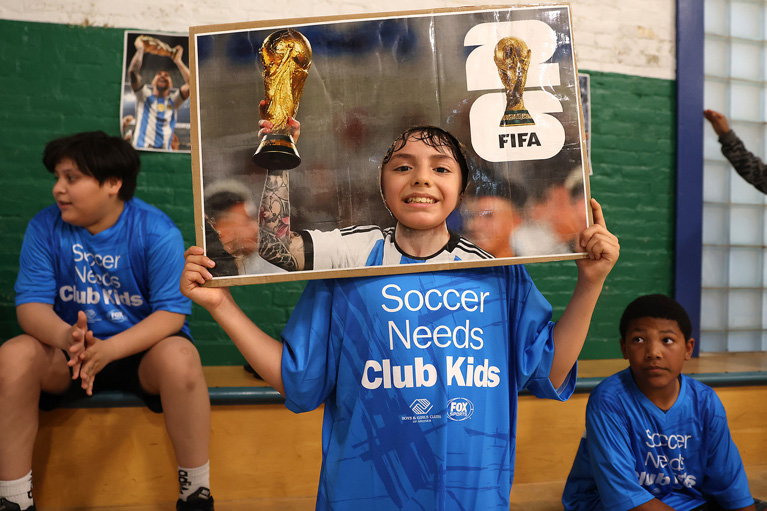Club kid playing in FIFA face-in-the-hole board.